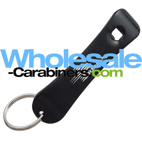 A black snowboard shaped bottle opener keychain with a silver split ring, shown on a white background with a large 'Wholesale-Carabiners.com' watermark overlay.