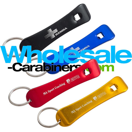 Four snowboard shaped bottle opener keychains in black, blue, red, and gold, arranged diagonally on a white background with a large 'Wholesale-Carabiners.com' watermark overlay.