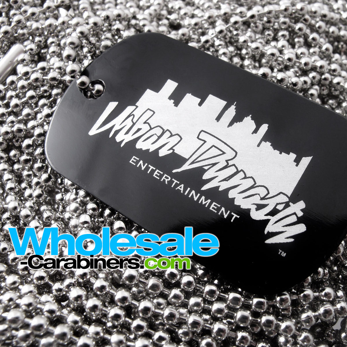 Close up of a black engraved dog tag for people, with a neck chain attached, customized with a logo, viewed slightly at an angle, and resting against a background of silver neck ball-chains.